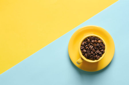 Coffee beans in yellow cup on blue and yellow background.