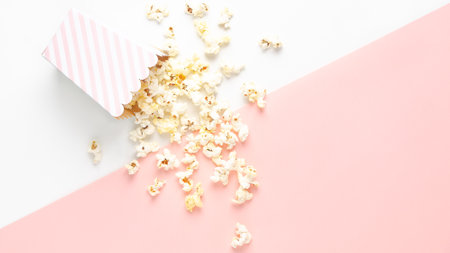A striped bucket of popcorn on white and pink background, top view and copy space.の写真素材