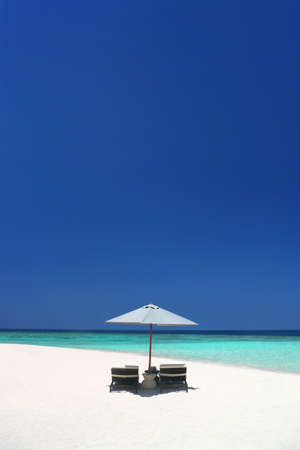 Beach chairs under an umbrella on a beautiful secluded beachの写真素材