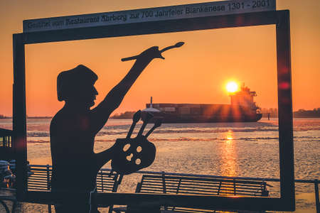 Abstract silhouette of a painter drawing sunset on the Elbe in Hamburg Germany. 03.03.2018.Ice drift in Blankenese. Blurred backgroundのeditorial素材