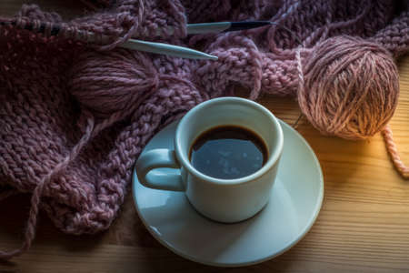A cup of coffee on the wooden table.A pause from knitting a cozy sweater.Wintertimeの写真素材