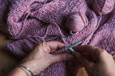 Knitting a cozy sweater. Female hands with knitting needles.Winter homemade concept