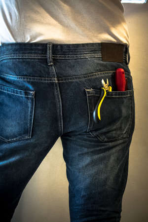 Worker in jeans with tools in his pocket while he worksの写真素材