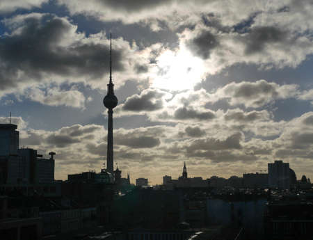 Atmospheric sunset over the Berlin cityscape with a dramatic cloudy sky and silhouette of the buildings and Fernsehturm TV Towerの写真素材