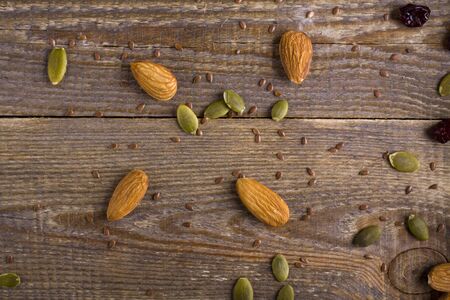 Grains, seeds, and the seeds scattered on a background of plank. almonds, pumpkin seeds, linseed and cranberry on wooden background.の写真素材