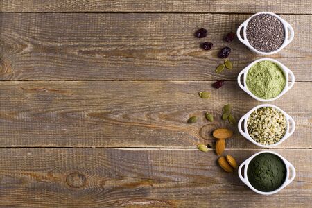 Superfood raw seeds and powder. Body building powders and health food on wooden background. Superfood served in small bowls.の写真素材