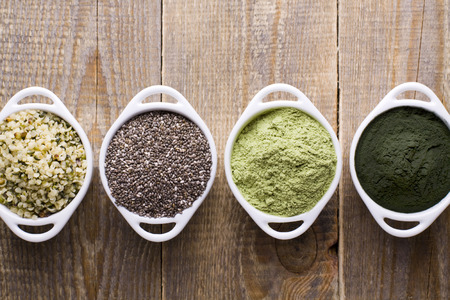 Superfood raw seeds and powder. Body building powders and health food on wooden background. Superfood served in small bowls.の写真素材