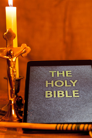 Digital  holy bible as a symbol of a new era. Scene from the cross, candles and sprinkler.の写真素材