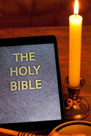 Digital  holy bible as a symbol of a new era. Scene from the cross, candles and sprinkler.の写真素材