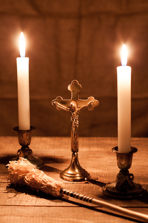 Gold cross with candles and sprinkler on wooden background.の写真素材