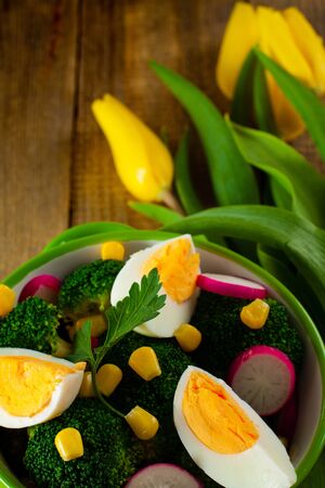 Broccoli salad with tulip flowers on wooden background.の写真素材