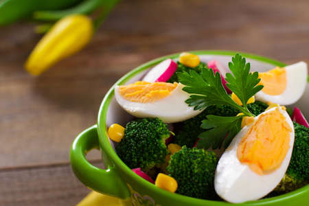Broccoli salad with tulip flowers on wooden background.の写真素材