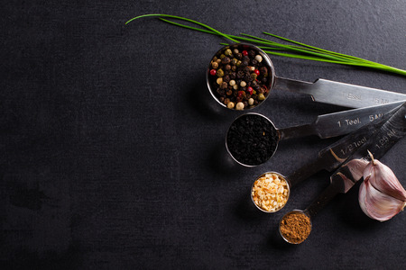 Spices in stainless steel measuring spoons and fresh herbs with copy space.の写真素材