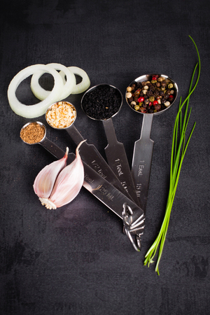 Spices in stainless steel measuring spoons and fresh herbs with copy space.の写真素材
