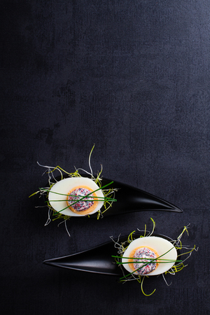 Appetizer on fingerspoon egg with caviaron black background.の写真素材