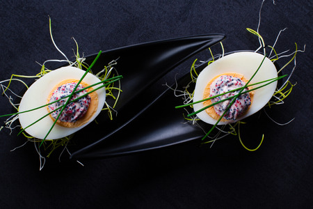 Appetizer on fingerspoon egg with caviaron black background.の写真素材