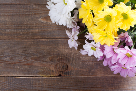 Pink, white and yellow oxeye daisy flowers bouquet on wooden background.の写真素材