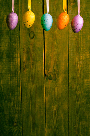 Colorful hanging easter eggs on wooden blur background.の写真素材