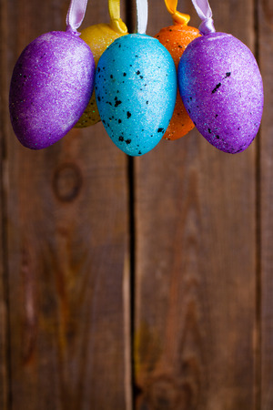 Colorful hanging easter eggs on wooden blur background.の写真素材