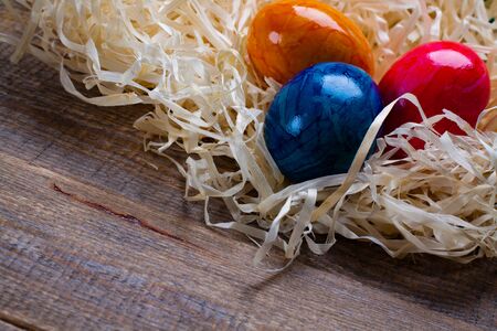 Easter eggs in hay on wooden background.の写真素材