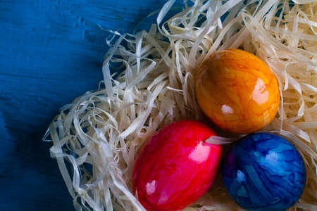 Easter eggs in hay on wooden background.の写真素材
