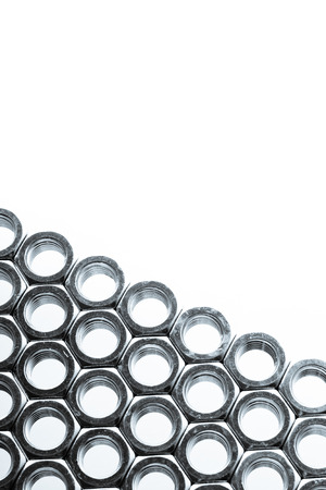 Nut screws tightly stacked next to each other on a flat surface. Nut isolated on white background.の写真素材