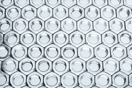 Nut screws tightly stacked next to each other on a flat surface. Nut isolated on white background.の写真素材
