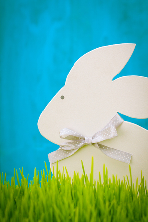 Figurine hare standing in the grass on a blue background.の写真素材