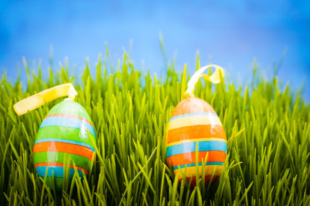 Scattered Easter eggs with bows in the grass and blue copy space.