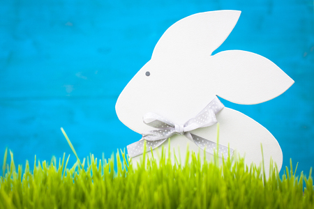 Figurine hare standing in the grass on a blue background.の写真素材
