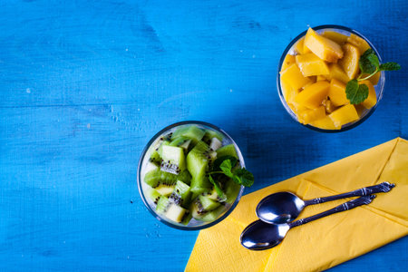 Dietetic dessert in the form of a fresh fruit salad with kiwi and peach with chia seeds and yoghurt served in a glass.Looking at the scene from above.の写真素材