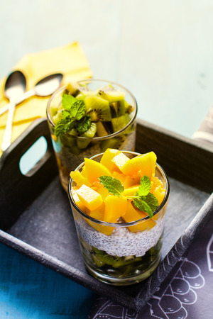 Dietetic dessert in the form of a fresh fruit salad with kiwi and peach with chia seeds and yoghurt served in a glass.の写真素材