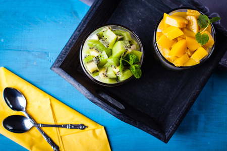 Dietetic dessert in the form of a fresh fruit salad with kiwi and peach with chia seeds and yoghurt served in a glass.Looking at the scene from above.の写真素材
