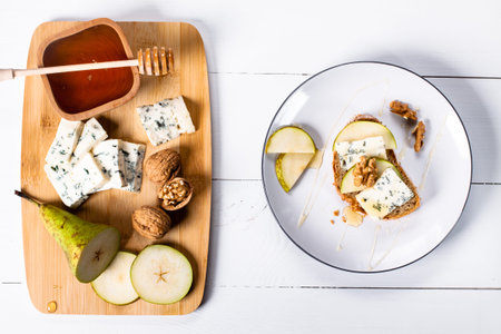 Sandwich with Blue cheese with slices of pear, nuts and honey on bamboo wooden cutting board and plate. Flat lay.の写真素材