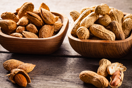 Hazelnuts, pistachios, peanuts and almonds on wooden bowls.の写真素材