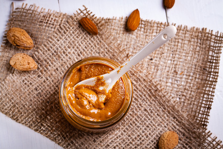 Homemade almond butter in a glass jar and a jute bag and napkin.の写真素材