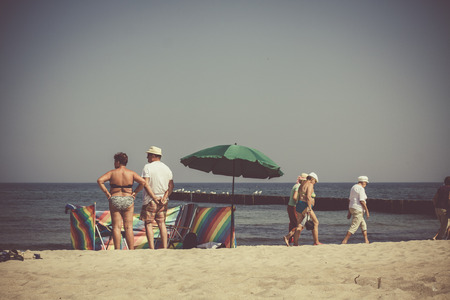 Photography in retro style showing sunbathers and walkers on the beach.の写真素材