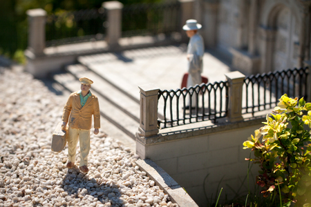Small figurine elegant men with luggage waiting on stairs.の写真素材