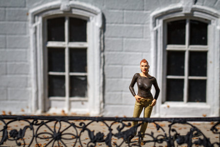 Small figurine of woman on balcony at background two windows.