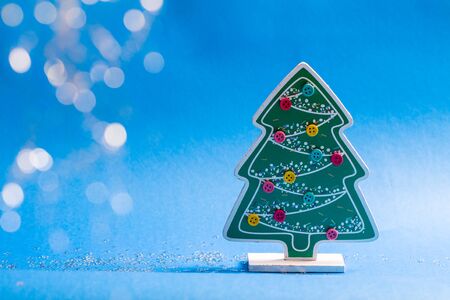 Wooden figurine of christmas tree with glued coloured buttons and glow stars and balls.の写真素材
