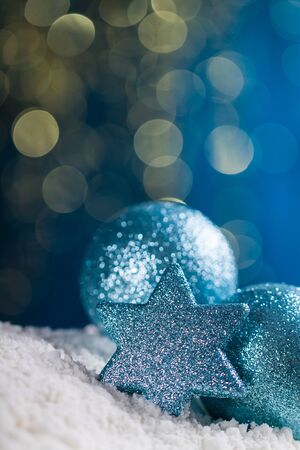 Christmas ball and star on snow and gold glitter on blue background.の写真素材