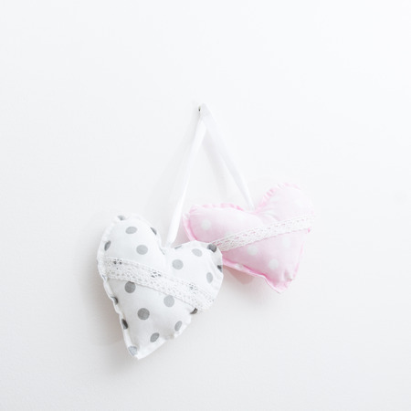 Two plush heart with dots, hanging on a white wall. The project on the card .の写真素材