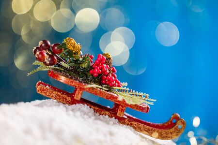 Sleigh with Christmas decoration on snow at blue background with gold glitter.の写真素材