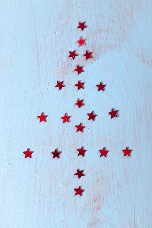 Christmas fir trees arranged of red stars on blue wooden background.の写真素材