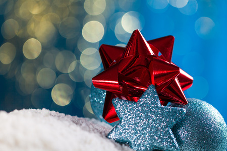 Christmas ball and star on snow and gold glitter on blue background.の写真素材
