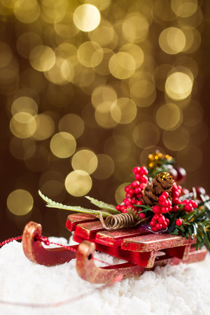 Decorative sleigh with roan-tree and Christmas tree branches, driving on snow, in the background the beautiful bokech balls.の写真素材