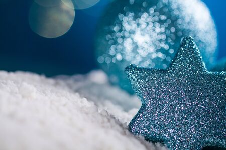 Christmas ball and star on snow and gold glitter on blue background.の写真素材