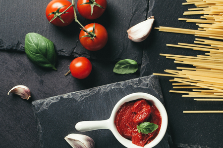 Food ingredients for Italian spaghetti on black slate stone background. Vegetarian version of pasta.の写真素材