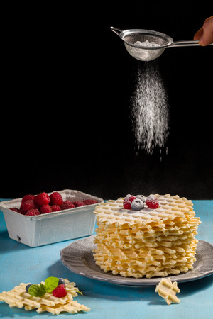 Belgian waffles with  sprinkled with icing sugar over black background.の写真素材