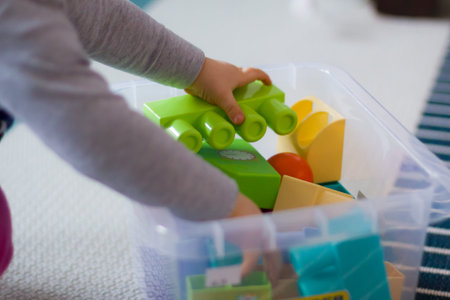 Small girl playing with colorful plastic bricks.